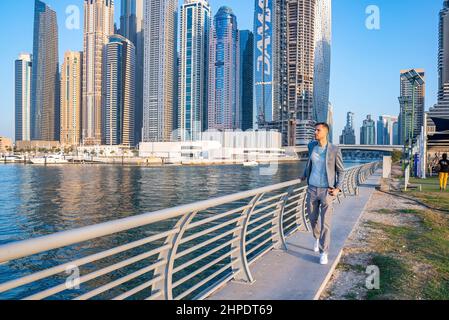 Junger Mann, der an der Promenade in Dubai Marina spazierengeht. Stockfoto