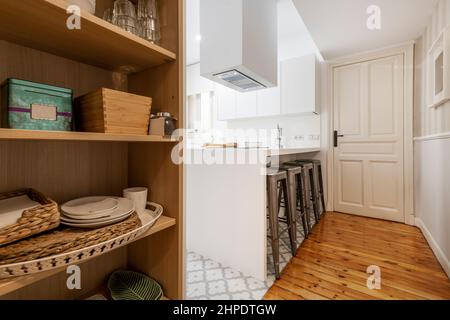 Küche mit großem einteiligen weißen Schrank und Geräten aus Edelstahl mit Holzböden und hydraulischem Steinzeug und Speisekammer mit Zubehör Stockfoto