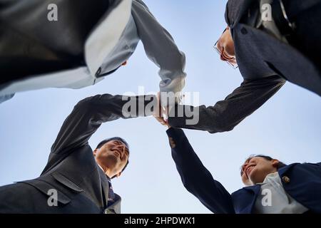 Eine Gruppe asiatischer Geschäftsleute, die ihre Hände zusammenlegen, um Teamgeist und Einheit zu zeigen Stockfoto