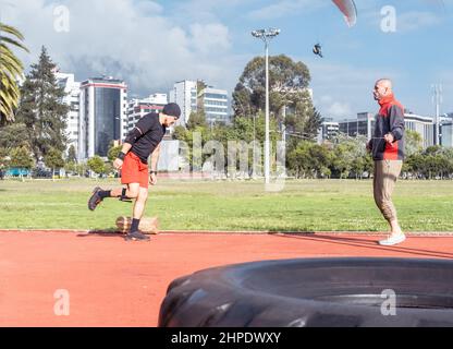 Zwei junge Athleten machen funktionelle Übungen, springen Seil und laufen in einem Park mit einem Gleitschirm, der am Himmel fliegt Stockfoto