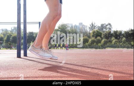 Nahaufnahme der Beine eines Mannes, der während eines Outdoor-Trainings in einem Park Seil hüpft Stockfoto