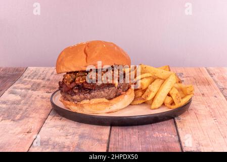 Rinderburger mit gebratenem Speck und Gemüseeintopf auf dem Fleisch mit hausgemachten Pommes frites Stockfoto