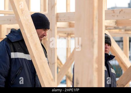 Bauherren in blauen Jacken mit Hauben auf der Installation einer Holzrutsche Stockfoto