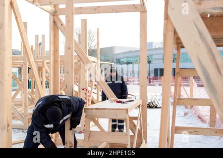 Bauherren in blauen Jacken mit Hauben auf der Installation einer Holzrutsche Stockfoto