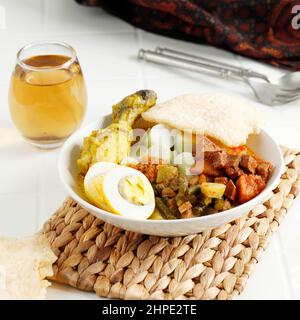 Lontong Sayur Medan, traditionelle indonesische Küche, Kokosnussbrühe mit Gemüse, Reiskuchen, Ei, Rendang Chili, Cracker Krupuk. Ausgewählter Fokus Stockfoto