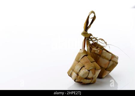 Ketupat Reisdumpling Spezialgericht serviert im Eid Mubarak. Isoliert auf weißem Hintergrund. Ketupat ist gekochter Reis mit jungen Kokosnussblättern, die Eid al umhüllten Stockfoto