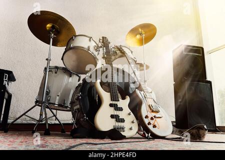 Rock and Roll-Band-Instrumente. E-Gitarre, Bassgitarre und RAM im Aufnahmestudio und in den Strahlen des hellen Sonnenlichts. Stockfoto