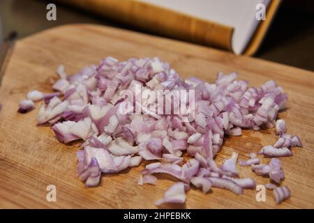 In Scheiben geschnittene lila Zwiebel auf einem Holzbrett. Bereiten Sie vor dem Kochen Zutaten und Gemüse vor Stockfoto