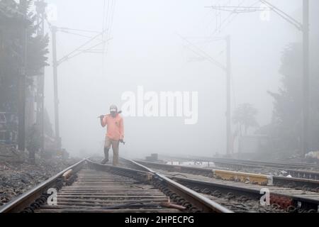 KALKUTTA, WESTBENGALEN, INDIEN. 21st. Februar 2022. 21. Februar 2022, Kalkutta, Westbengalen, Indien: Ein Eisenbahner überprüft die Gleise inmitten eines dichten fogg. Eisenbahn-, Flug-, Steg-Dienste wurden aufgrund der schlechten Sichtverhältnisse durchgeführt. (Bild: © Dipayan Bose/ZUMA Press Wire) Stockfoto