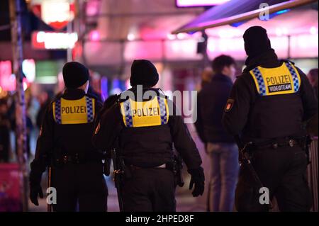 Hamburg, Deutschland. 20th. Februar 2022. Auf der Reeperbahn laufen Polizeibeamte zwischen Partygängern. In Hamburg trat am Samstag die erste Stufe der dreistufigen Aufhebung aller von Bund und Ländern geplanten Corona-Maßnahmen in Kraft. Geimpfte und wiedergeborene Menschen können sich seit Mitternacht wieder in unbegrenzter Zahl privat treffen. Außerdem wurden das Verbot des Alkoholverkaufs für Einzelhändler und die Ausgangssperre in Restaurants aufgehoben. Quelle: Jonas Walzberg/dpa/Alamy Live News Stockfoto