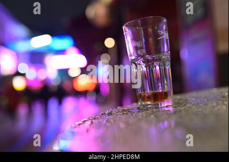 Hamburg, Deutschland. 20th. Februar 2022. Auf einem Tisch vor einem Pub in der Großen Freiheit bei der Reeperbahn steht ein Glas. In Hamburg trat am Samstag die erste Stufe der dreistufigen Aufhebung aller Corona-Maßnahmen in Kraft. Geimpfte und wiedergeborene Menschen können sich seit Mitternacht wieder in unbegrenzter Zahl privat treffen. Darüber hinaus wurden das Alkoholverbot für Einzelhändler und die Ausgangssperre im Gastronomiegewerbe aufgehoben. Quelle: Jonas Walzberg/dpa/Alamy Live News Stockfoto