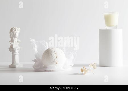 Badebombe und Kerze auf dem Podium auf weißem Hintergrund. Stillleben für die Wanddekoration im Resort Spa oder Salon. Spa, Relax, Wellness-Konzept. Stockfoto