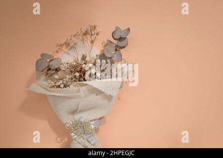 Getrockneter Blumenstrauß als Geburtstagsgeschenk auf beige neutralem Hintergrund. Speicherplatz kopieren. Stockfoto