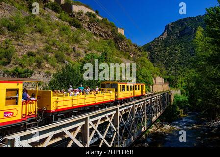 Der kleine gelbe Zug (Le Petit Train Jaune), der durch Villefranche-de-Conflent, Frankreich, fährt Stockfoto
