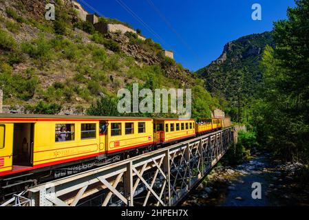 Der kleine gelbe Zug (Le Petit Train Jaune), der durch Villefranche-de-Conflent, Frankreich, fährt Stockfoto