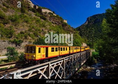 Der kleine gelbe Zug (Le Petit Train Jaune), der durch Villefranche-de-Conflent, Frankreich, fährt Stockfoto