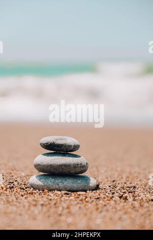 Felsbalancierung am Meeresstrand. Kieselsteinpyramide an sandigen Ufern. Stabiler Stapel oder Haufen im weichen Fokus mit Bokeh, Nahaufnahme. Zen-Balance, Minimalismus Stockfoto