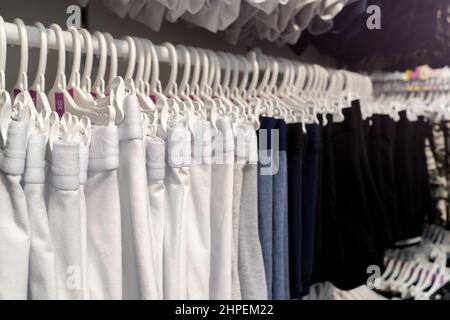 Modische Kleidung auf Kleiderbügeln auf einem Kleiderständer auf farbigem Hintergrund Stockfoto