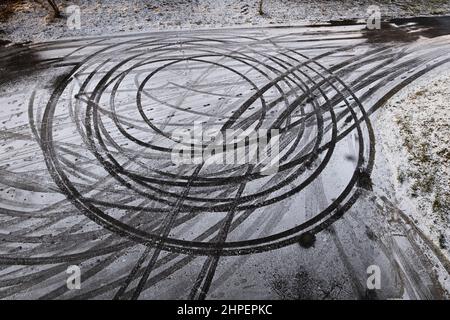 Abstrakte Kreise im Schnee, Autodrift-Skid-Markierungen auf der winterlichen Rennbahn. Stockfoto