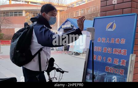 Peking, China. 21st. Februar 2022. Ein Student erhält eine Körpertemperatur-Kontrolle, bevor er den Campus der Beijing Space Middle School in Peking, der Hauptstadt Chinas, am 21. Februar 2022 betreten wird. Grund- und Sekundarschulen in Peking haben am Montag das neue Semester begonnen. Kredit: Li Xin/Xinhua/Alamy Live Nachrichten Stockfoto