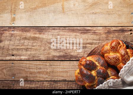 Shabbat Shalom. Brotchallah mit Sesamsamen und Mohn auf Holzgrund. Traditionelles jüdisches Brot für Sabbat und Feiertage. Rustikaler Koncep Stockfoto