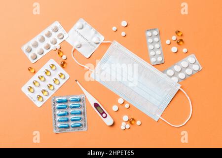 Gesichtsschutzmasken oder OP-Masken, Medikamentententabletten und Thermometer auf dem Tischhintergrund. Coronavirus-Krankheit. Corona-Virus-Konzept. Platz für Text Stockfoto