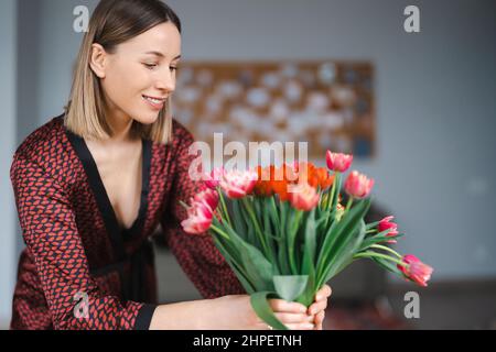 Schöne Frau, die von ihrem Husbant zu Hause Blumen arrangiert, glücklich und fröhlich Stockfoto