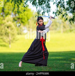 Junge asiatische Frau im traditionellen Kimono trainiert Kampftechniken mit Katana-Schwert, Samurai-Kriegermädchen Stockfoto