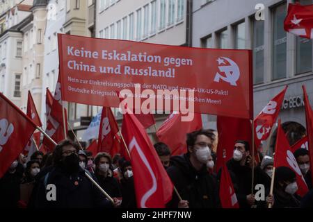 München, Deutschland. 19th. Februar 2022. Teilnehmer mit rotem Banner „Keine Eskalation gegen China und Russland“ und roten Fahnen. Am 19. Februar 2022 versammelten sich Tausende von Teilnehmern, um gegen die Münchner Sicherheitskonferenz, gegen Krieg und NATO und für den Frieden zu demonstrieren. In diesem Jahr werden auf der MSC Themen wie der Russland-Ukraine-Konflikt behandelt, ohne dass Russland daran teilnimmt. (Foto: Alexander Pohl/Sipa USA) Quelle: SIPA USA/Alamy Live News Stockfoto