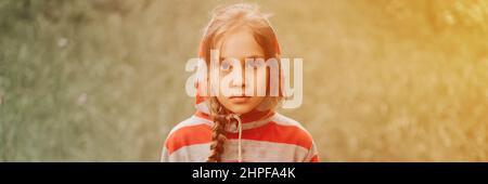 Portrait Gesicht von aufgeregt oder konzentriert nachdenklich Scowl acht Jahre altes Kind Mädchen in Kapuze von gestreiften Hoodie in der Wald Natur. Vorpubertal Kinder Geist p Stockfoto