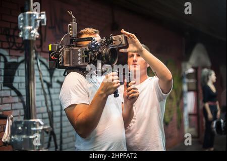 Hinter den Kulissen. Kameramann, der die Filmszene mit seiner Kamera auf einem Outdoor-Set gedreht hat. Fotografie Regisseur im Film Filmemachen Aktion Stockfoto