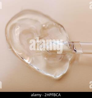 Transparentes Gel-Hyaluron-Serum in Pipette auf beigem Hautton-Hintergrund. Wasser Textur Gel Oberfläche der kosmetischen Haut Gesundheitsprodukt Probe Stockfoto