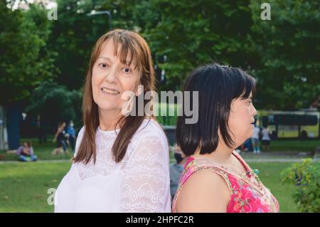 Zwei Erwachsene latina kaukasische Frauen zusammen auf einem platz suchen in verschiedene Richtungen. Lifestyle-Konzept. Stockfoto