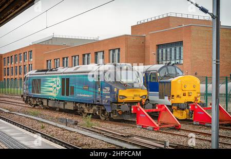 Zwei Diesellokomotiven stehen auf einem Abstellgleis vor einem Backsteingebäude. Ein trüber Himmel ist über uns. Stockfoto