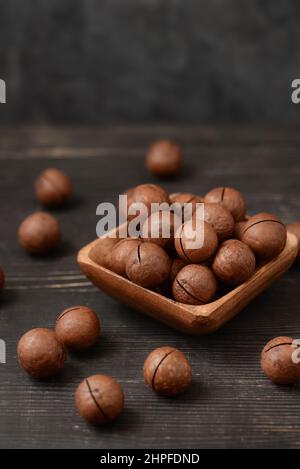 Schale mit Macadamia-Nüssen auf schwarzem Holztisch Stockfoto