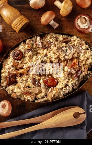 Risotto ai funghi, Pilzrisotto, rustikaler Reis mit Pilzen, über Kopf auf dunklem Holzhintergrund geschossen Stockfoto