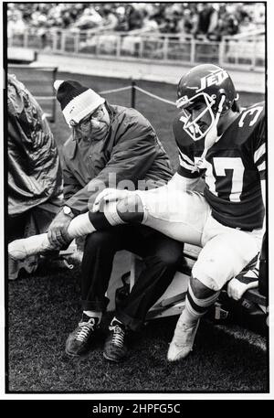 Der Pionier der Sportmedizin, Dr. James Nichola, untersucht einen Jets-Spieler auf der Bank während eines Spiels im Shea Stadium 1978 in Flushing, Queens, New York. Stockfoto