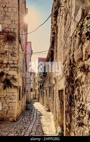 Hübsche alte Steinhäuser und Straßenlaterne in der engen Seitenstraße von Trogir, Kroatien Stockfoto