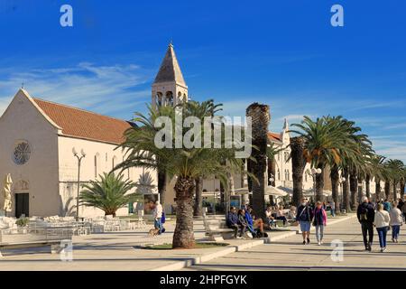 Trogir, Kroatien - Menschen, die an einem sonnigen Tag entlang der Riva oder Promenade in der Altstadt spazieren Stockfoto
