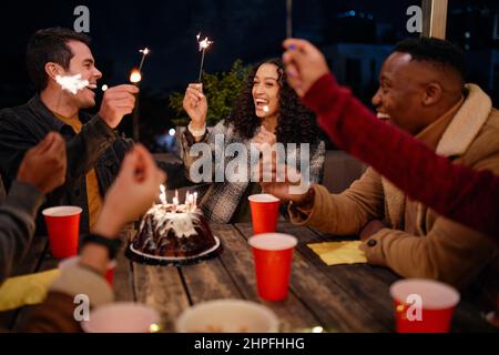 Eine Gruppe von jungen Erwachsenen, die auf der Dachparty Happy Birthday singen, Wunderkerzen und gute Zeiten. Stockfoto