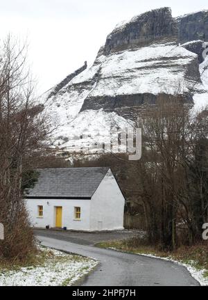 Ferienhaus auf ländlicher Straße am Fuße der schneebedeckten Eagle's Rock Klippe in Glenade, County Leitrim, Irland Stockfoto