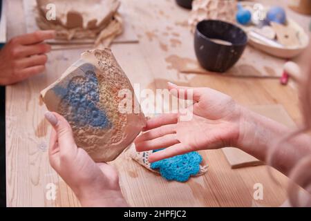 Herstellung einer durchbrochenen Tafel aus Ton mit einer gestrickten Serviette. Stockfoto