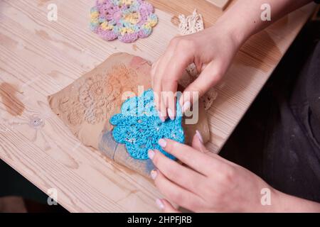 Frauenhände machen Keramik-Panto. Herstellung von Keramik. Ein Muster auf einem Panno zusammendrücken. Stockfoto