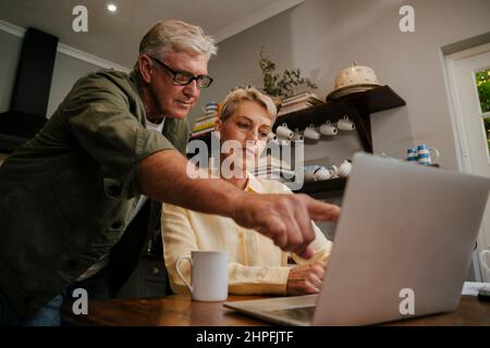 kaukasisches Rentnerpaar, das zu Hause arbeitet und Online-Zahlungen macht Stockfoto