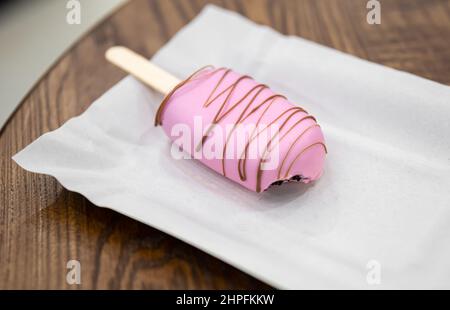 Mousse Dessert in Form von Eis mit Eis bedeckt mit rosa Schokolade. Stockfoto