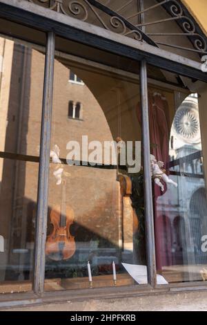 Schaufenster eines Geigenbauers: Handgefertigte Violinen im Schaufenster und Spiegelung der Kathedrale von Cremona, Italien. Stockfoto