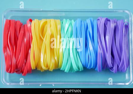 regenbogenfarbe Gummibänder auf farbigem Hintergrund Stockfoto