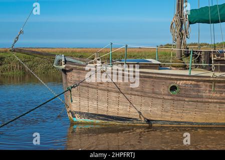 Altes Segelboot aus Holz an seinen Anlegestellen im alten Hafen von Thornham, wenn die Flut an einem sonnigen Frühlingsabend eintrifft. Thornham, Norfolk, England, Großbritannien Stockfoto