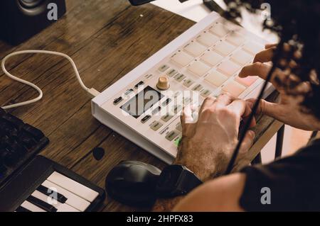 Rückansicht des kaukasischen Mannes, der in seinem Heimstudio Beats auf einem Midi-Controller macht, elektronische Musik und urbane Musik produziert, Musik komponiert und Comme komponiert Stockfoto