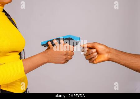 Zugeschnittenes Bild des Kunden, der mit einer Kreditkarte mit dem Zahlungsterminal bezahlt Stockfoto